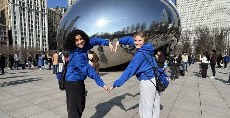 students posing with their arms bent to form a heart in front of Cloudgate/the bean