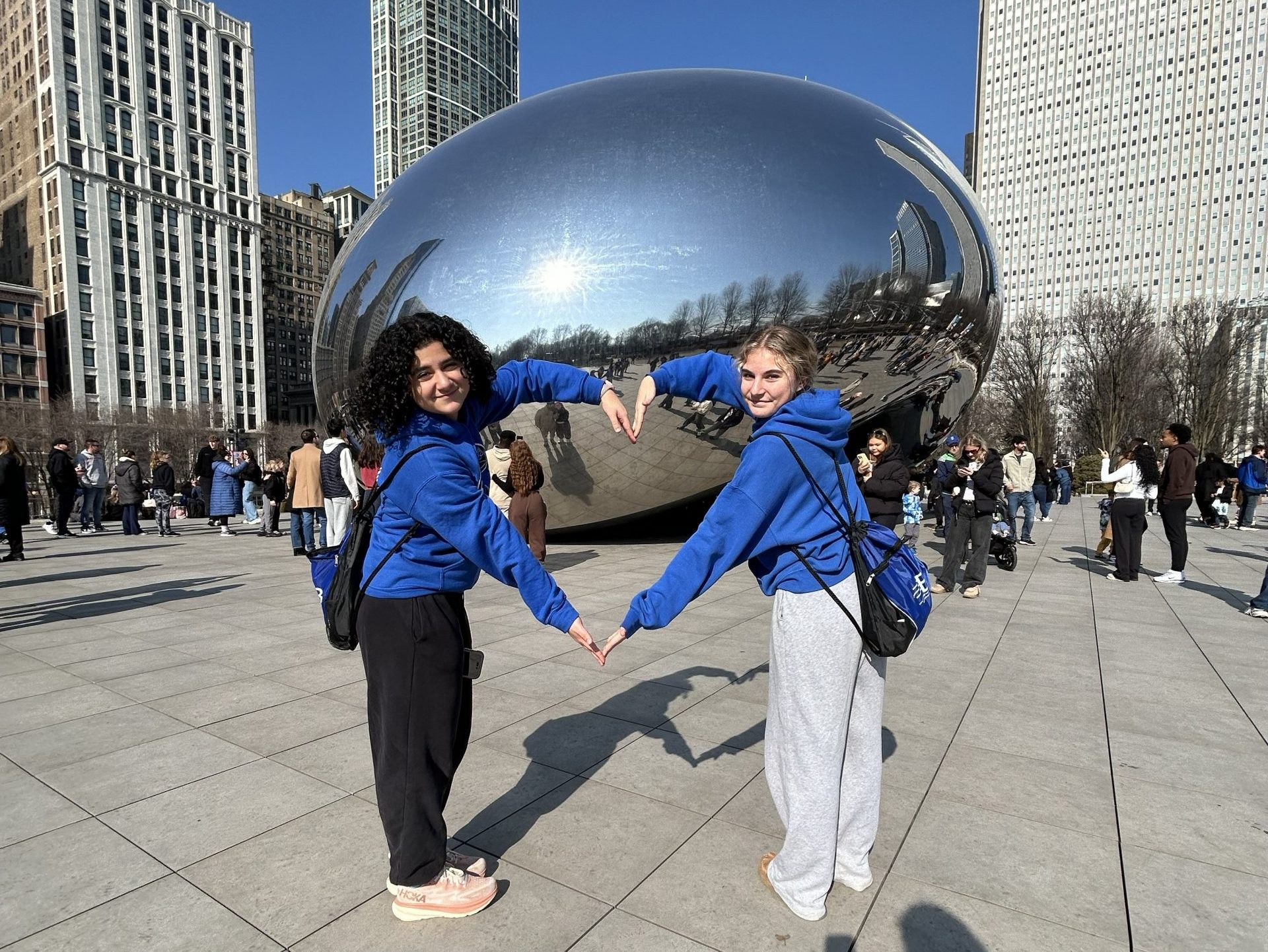 students posing with their arms bent to form a heart in front of Cloudgate/the bean